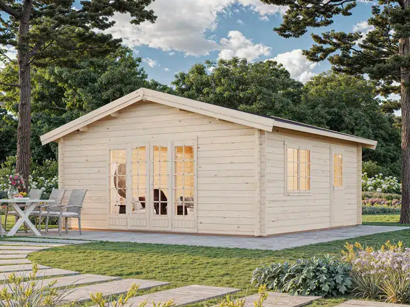 Abris de jardin en bois clair avec grandes portes vitrées et fenêtres, installé sur une dalle dans un jardin arboré.