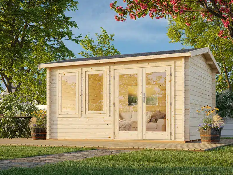 Abri de jardin en bois clair avec porte-fenêtre et fenêtres vitrées, posé sur la pelouse parmi les arbres.