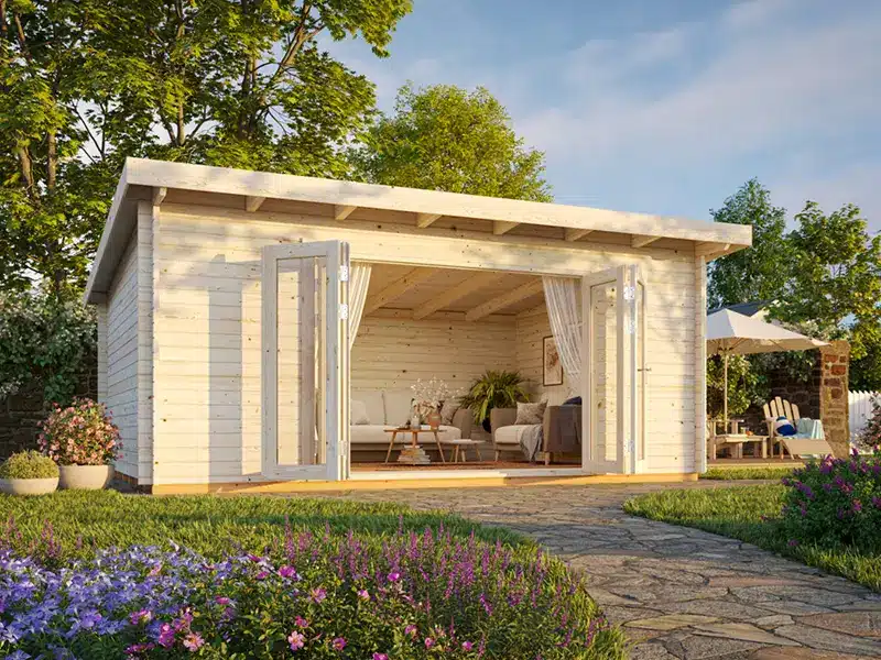Chalet de jardin en bois avec terrasse ouverte et mobilier d'extérieur, entouré d’un jardin fleuri.