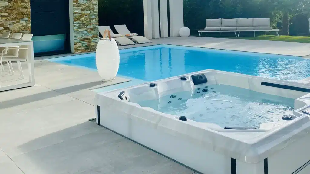 Piscine extérieure et spa adjacents sur une terrasse contemporaine, entourés de mobilier de jardin.