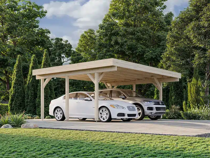 Carport en bois couvrant deux voitures sur une allée, entouré d’un jardin verdoyant et d’arbres.