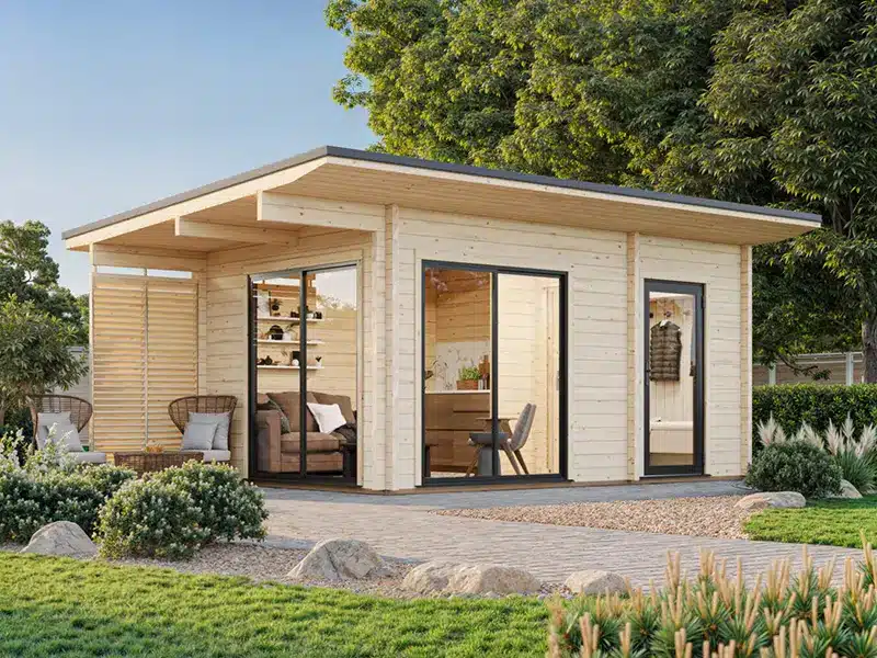 Abris de jardin en bois au design contemporain avec toit à débord et grandes portes-fenêtres, sur une terrasse entourée de verdure.
